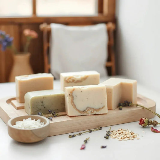 Handmade soap bars with subtle swirls and dried botanicals on a wooden tray.
