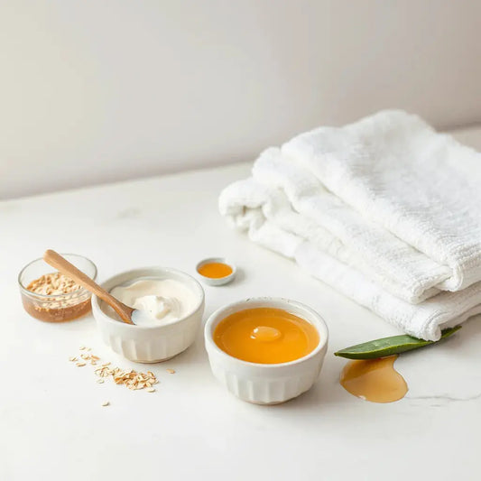 Natural face masks in ceramic bowls with skincare ingredients on a clean bathroom counter